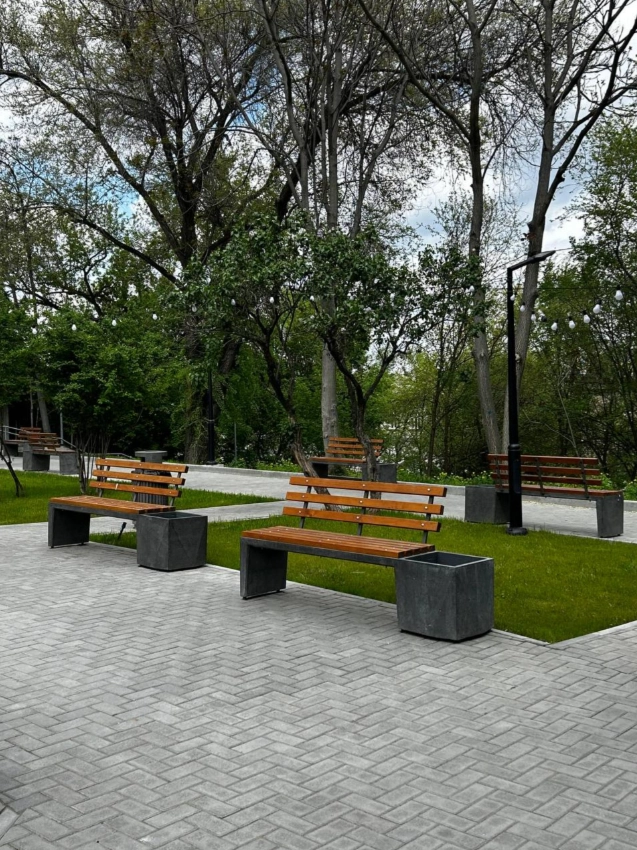 Бетонная скамейка с деревянными спинками и горшками